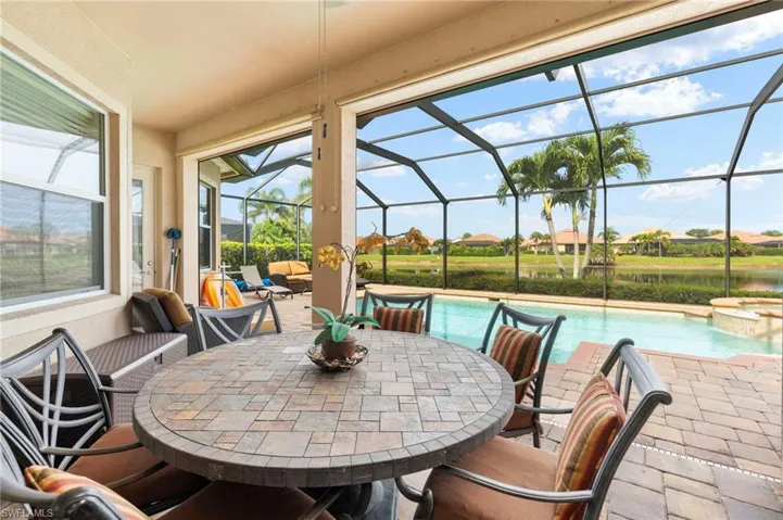 View of patio with a pool with connected hot tub, glass enclosure, and a water view