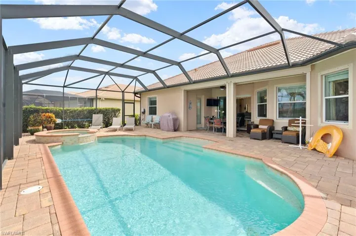 View of pool featuring a patio area, a pool with connected hot tub, glass enclosure, area for grilling, and ceiling fan