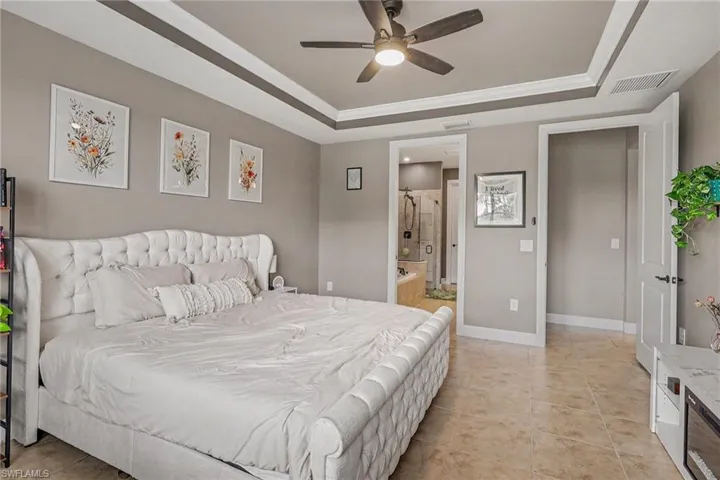 Tray ceiling with crown molding, integrated ceiling fan, and tile flooring