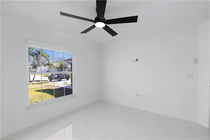 Empty room featuring ceiling fan and a wealth of natural light