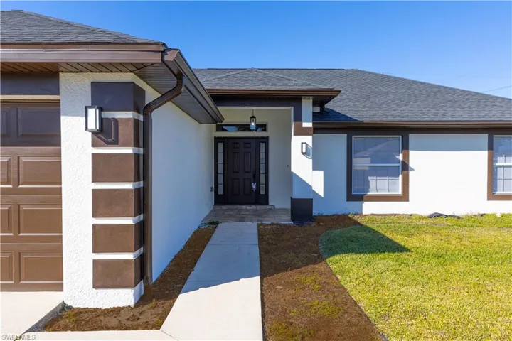 Entrance to property with a garage and a yard