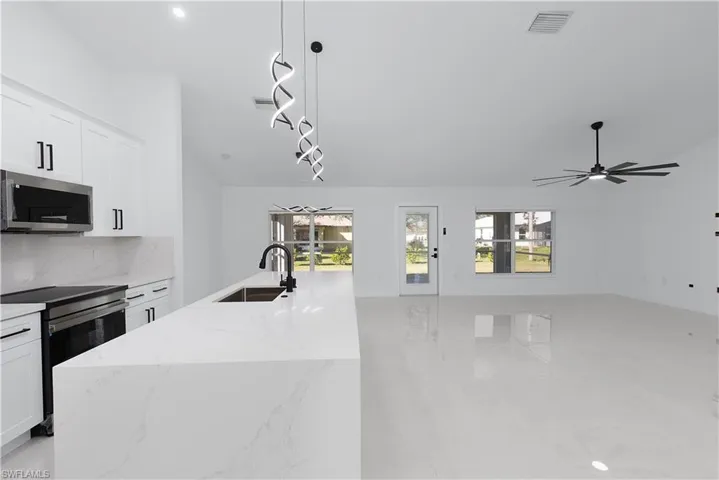 Kitchen featuring ceiling fan, sink, an island with sink, white cabinets, and appliances with stainless steel finishes