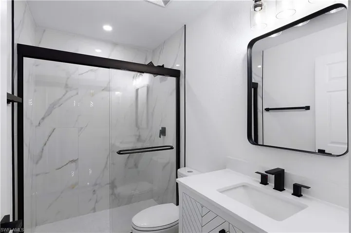 Bathroom with vanity, a shower with shower door, and toilet
