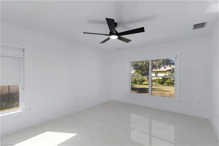 Empty room featuring ceiling fan and a wealth of natural light