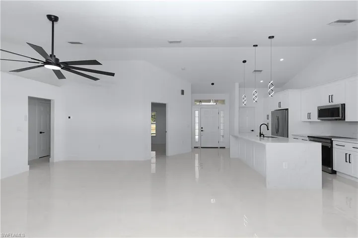Kitchen with white cabinetry, sink, decorative light fixtures, a kitchen island with sink, and appliances with stainless steel finishes