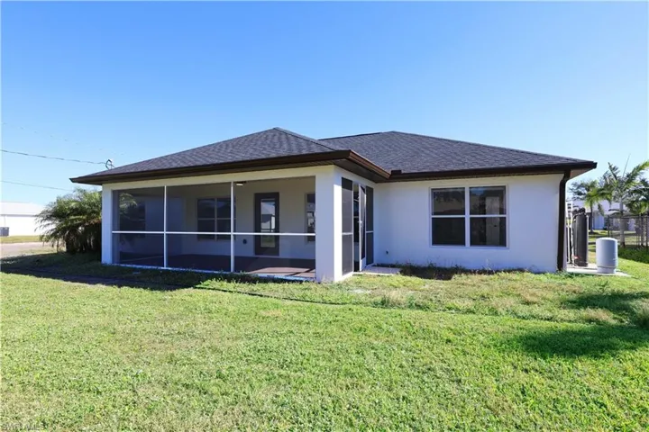 Back of house featuring a lawn and a sunroom