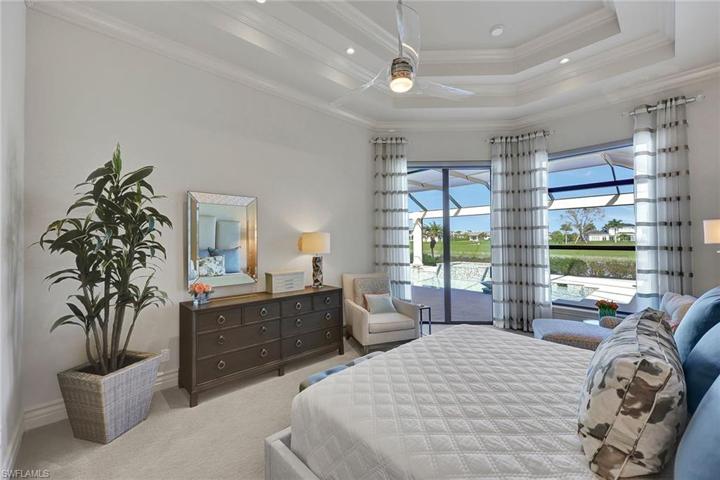 The Primary bedroom opens to the pool deck, with beautiful silhouette shades and custom drapes