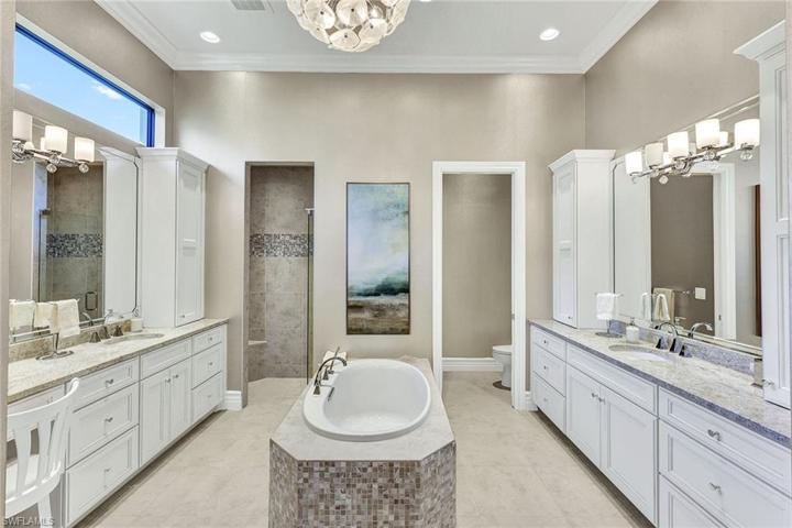 The primary ensuite bath offers his and hers vanities, sinks, water closets, shower and soaking tub