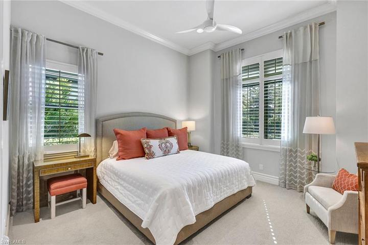 King size guest bedroom offers custom window coverings and plantation shutters