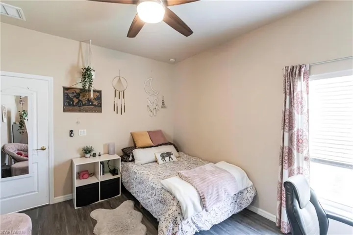 Bedroom with baseboards, multiple windows, and wood finished floors