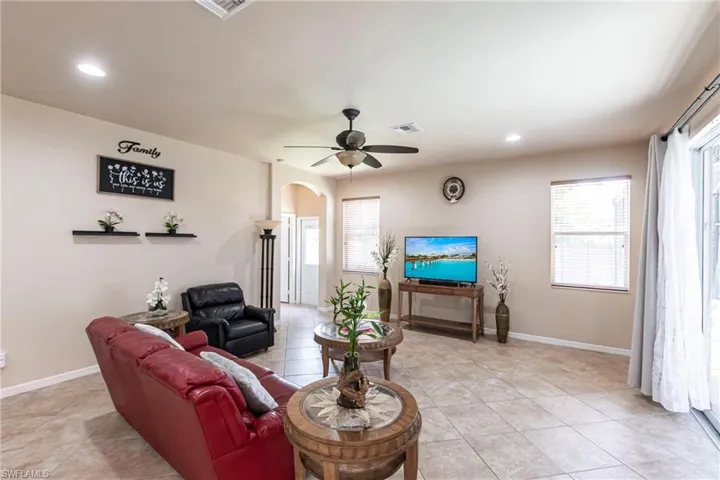 Living area with a healthy amount of sunlight, arched walkways, light tile patterned flooring, and visible vents
