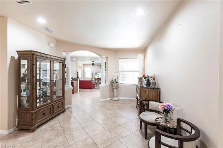 Corridor featuring arched walkways, recessed lighting, decorative columns, light tile patterned floors, and visible vents