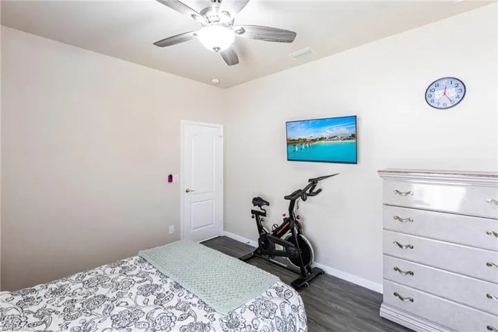 Bedroom featuring baseboards, a ceiling fan, dark wood-style flooring, and visible vents
