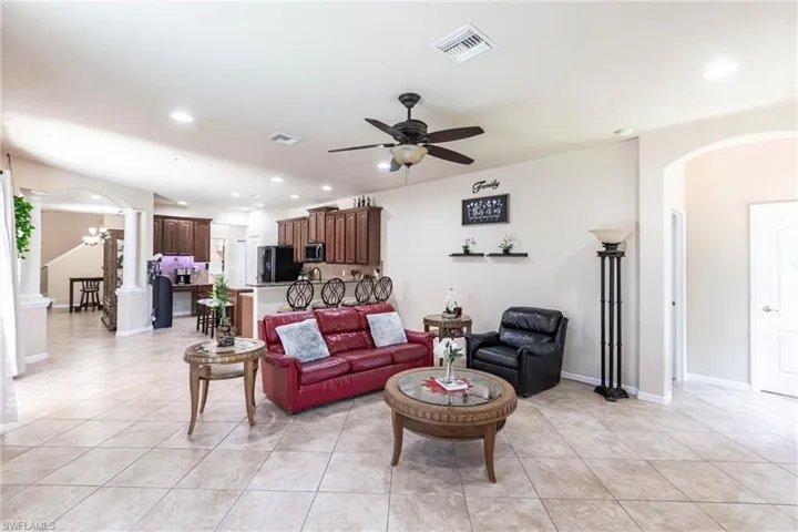 Living room featuring arched walkways, a ceiling fan, decorative columns, and light tile patterned flooring