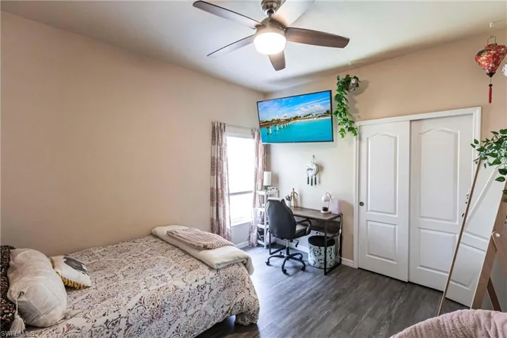 Bedroom featuring a closet, baseboards, ceiling fan, and dark wood-style floors