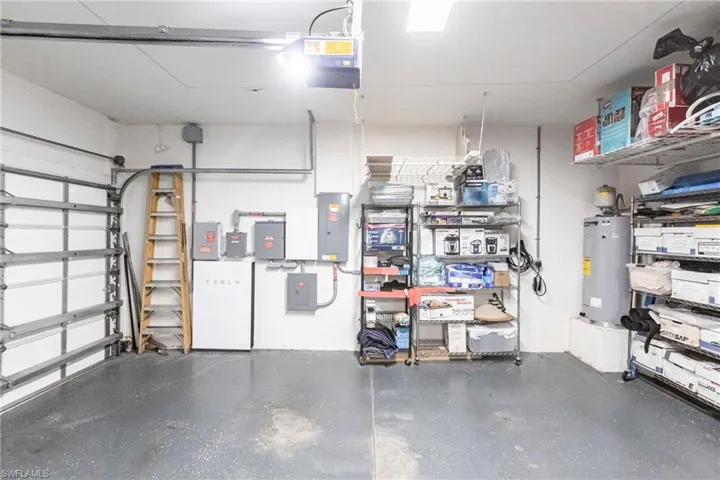 Garage with a garage door opener, water heater, and electric panel