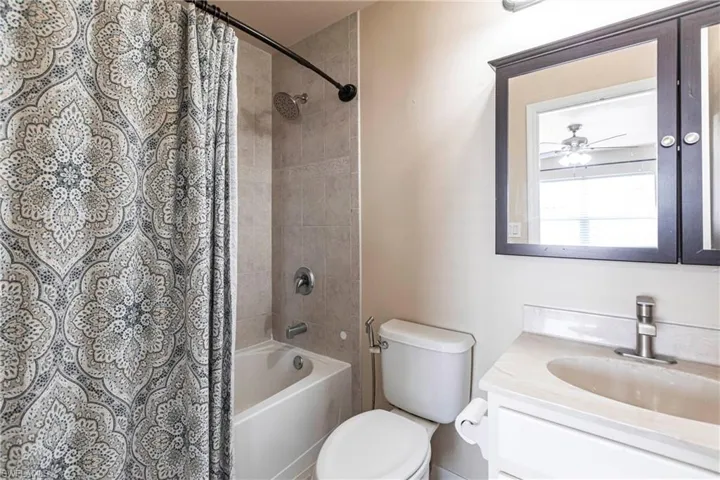 Bathroom featuring toilet, shower / bath combo, and vanity