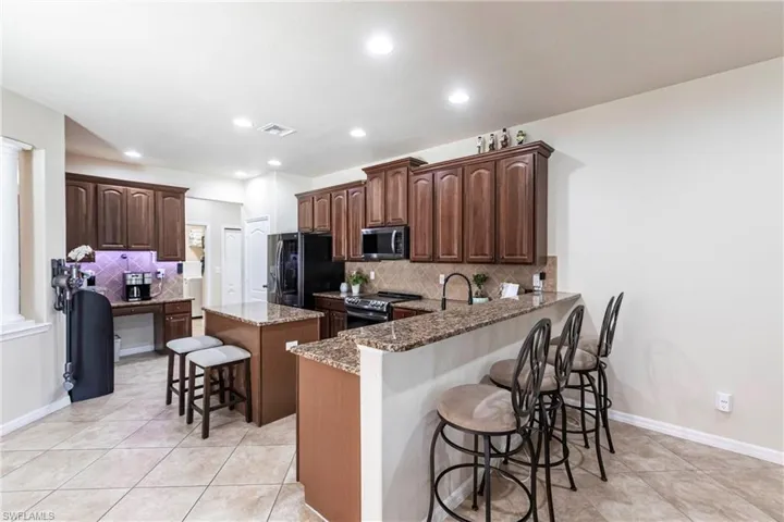 Kitchen featuring a kitchen island, a kitchen bar, visible vents, appliances with stainless steel finishes, and light tile patterned flooring