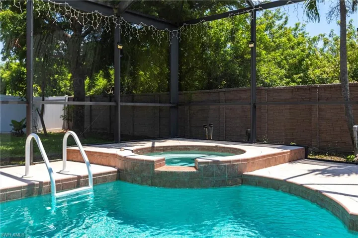 Outdoor pool featuring an in ground hot tub and fence