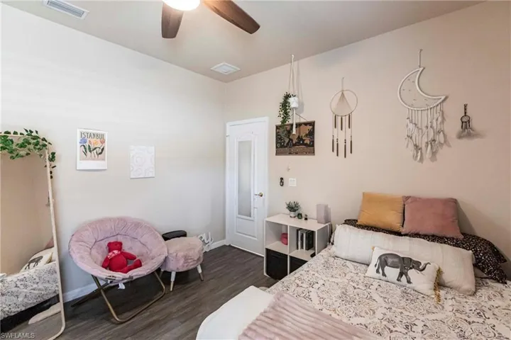 Bedroom with baseboards, ceiling fan, dark wood-style flooring, and visible vents