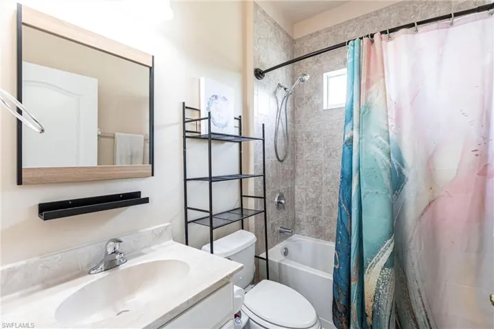 Bathroom with toilet, shower / bath combo, and vanity