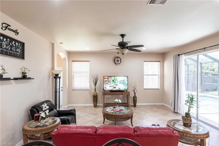 Living room with light tile patterned floors, plenty of natural light, and a ceiling fan