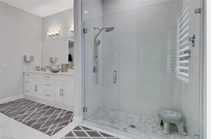 Full bath featuring a shower stall, double vanity, and tile patterned floors