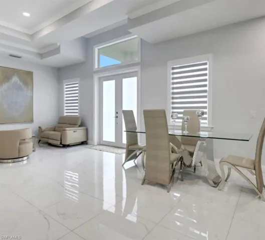 Dining area featuring french doors, crown molding, marble finish flooring, and a raised ceiling
