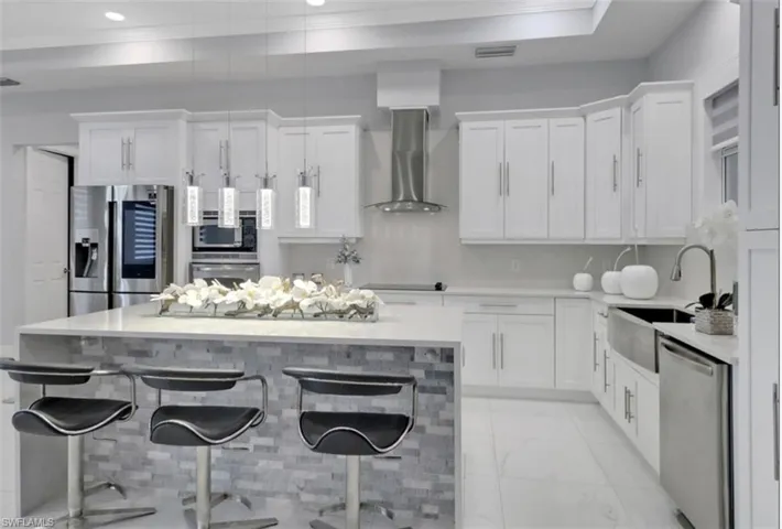 Kitchen featuring ornamental molding, white cabinets, a center island, light countertops, and appliances with stainless steel finishes