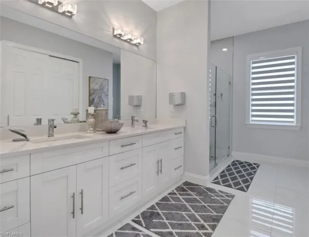 Bathroom featuring tile patterned floors, double vanity, and a stall shower
