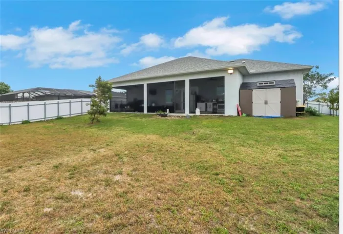 Back of property featuring a sunroom and a shed