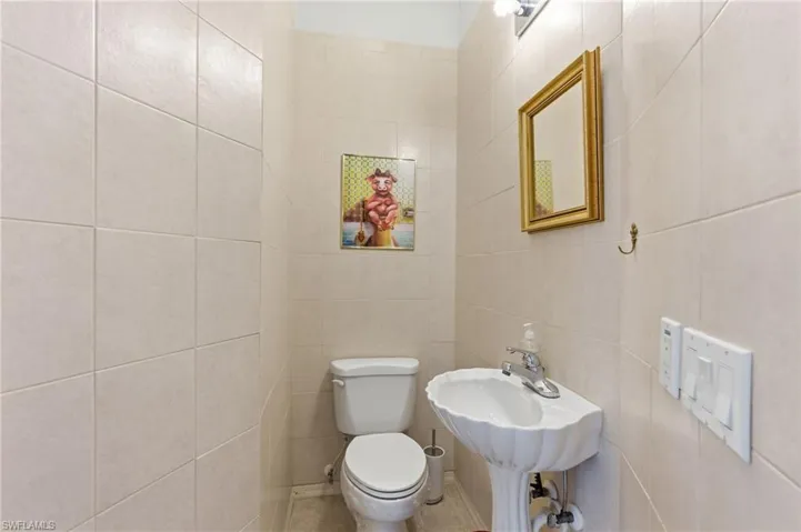 Half bath with toilet and tile walls