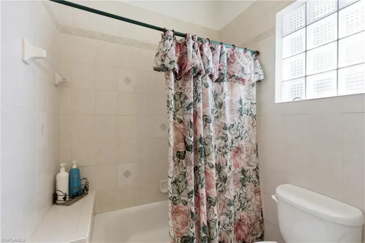 Full bath featuring shower / tub combo with curtain and tile walls