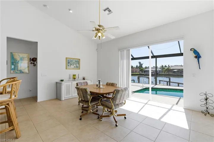 Dining space featuring vaulted ceiling, a water view, a ceiling fan, a sunroom, and light tile patterned flooring