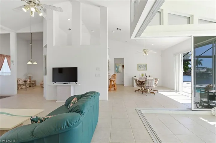 Living room with ceiling fan, vaulted ceiling, light tile patterned floors, and recessed lighting