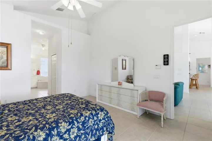 Bedroom with light tile patterned floors, lofted ceiling, and ceiling fan