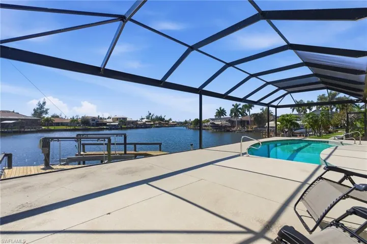 Outdoor pool with a boat dock, a sunroom, a lanai, and a water view