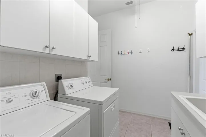 Laundry room with cabinet space, light tile patterned flooring, and washer and clothes dryer