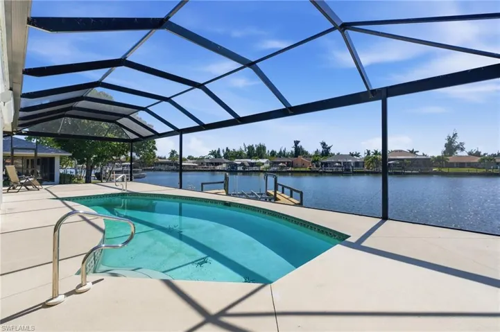 Swimming pool featuring glass enclosure, a sunroom, a patio area, a boat dock, and a water view