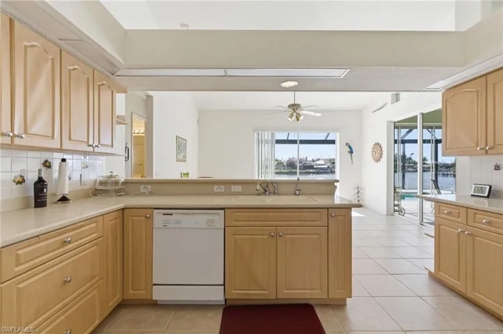 Kitchen featuring decorative backsplash, light wood finish cabinetry, dishwasher, a peninsula, and ceiling fan
