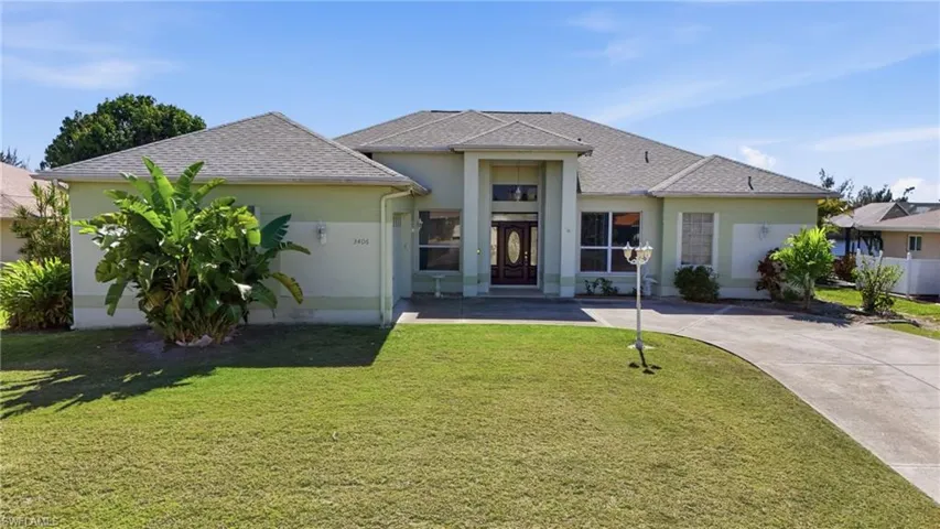View of front facade with a front yard, roof with shingles, and stucco siding
