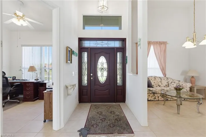 Entrance foyer with a ceiling fan, light tile patterned floors, suspended lighting, and a high ceiling