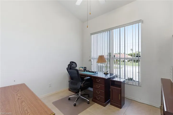 Office space featuring vaulted ceiling, a ceiling fan, and light tile patterned floors