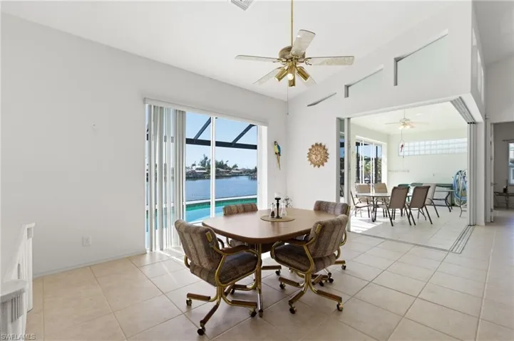 Dining space with a sunroom, plenty of natural light, lofted ceiling, a ceiling fan, and light tile patterned flooring