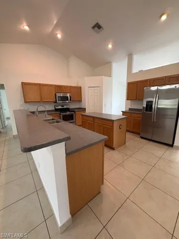 Kitchen with dark countertops, refrigerator, a peninsula, wood finish cabinetry, and recessed lighting