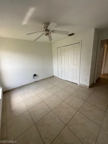 Unfurnished bedroom featuring a closet, ceiling fan, and light tile patterned floors