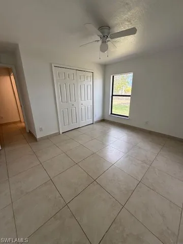 Unfurnished bedroom featuring a closet, ceiling fan, a textured ceiling, and light tile patterned floors