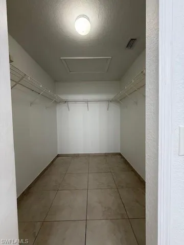 Walk in closet with attic access and light tile patterned flooring