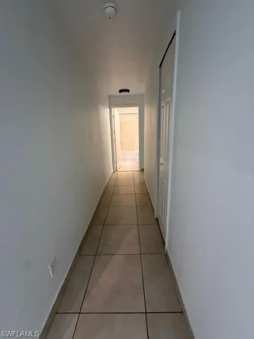 Hall featuring light tile patterned flooring and baseboards