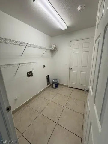 Laundry room featuring a textured ceiling, washer hookup, and hookup for an electric dryer